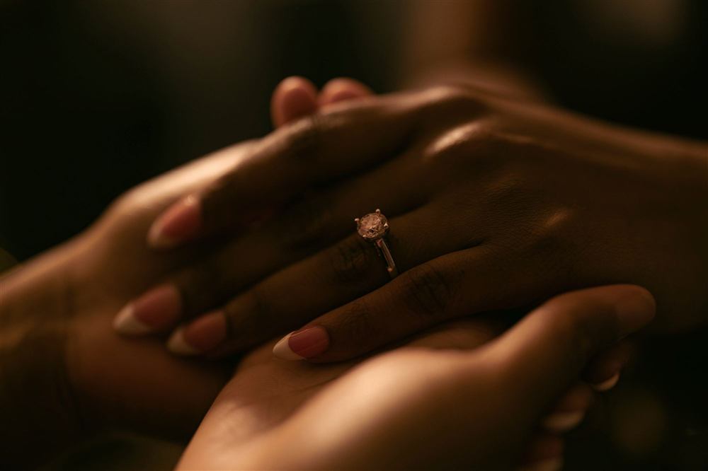 Close-up of hands holding, an engagement ring catching warm light