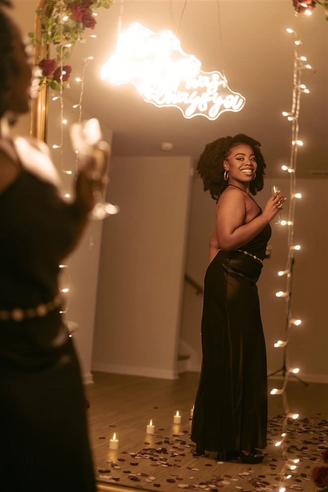 A woman in black beneath a chandelier at a candlelit proposal