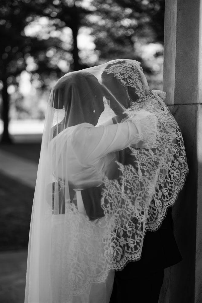 A black-and-white portrait of a bride and groom sharing a quiet moment beneath her lace veil at the DC War Memorial